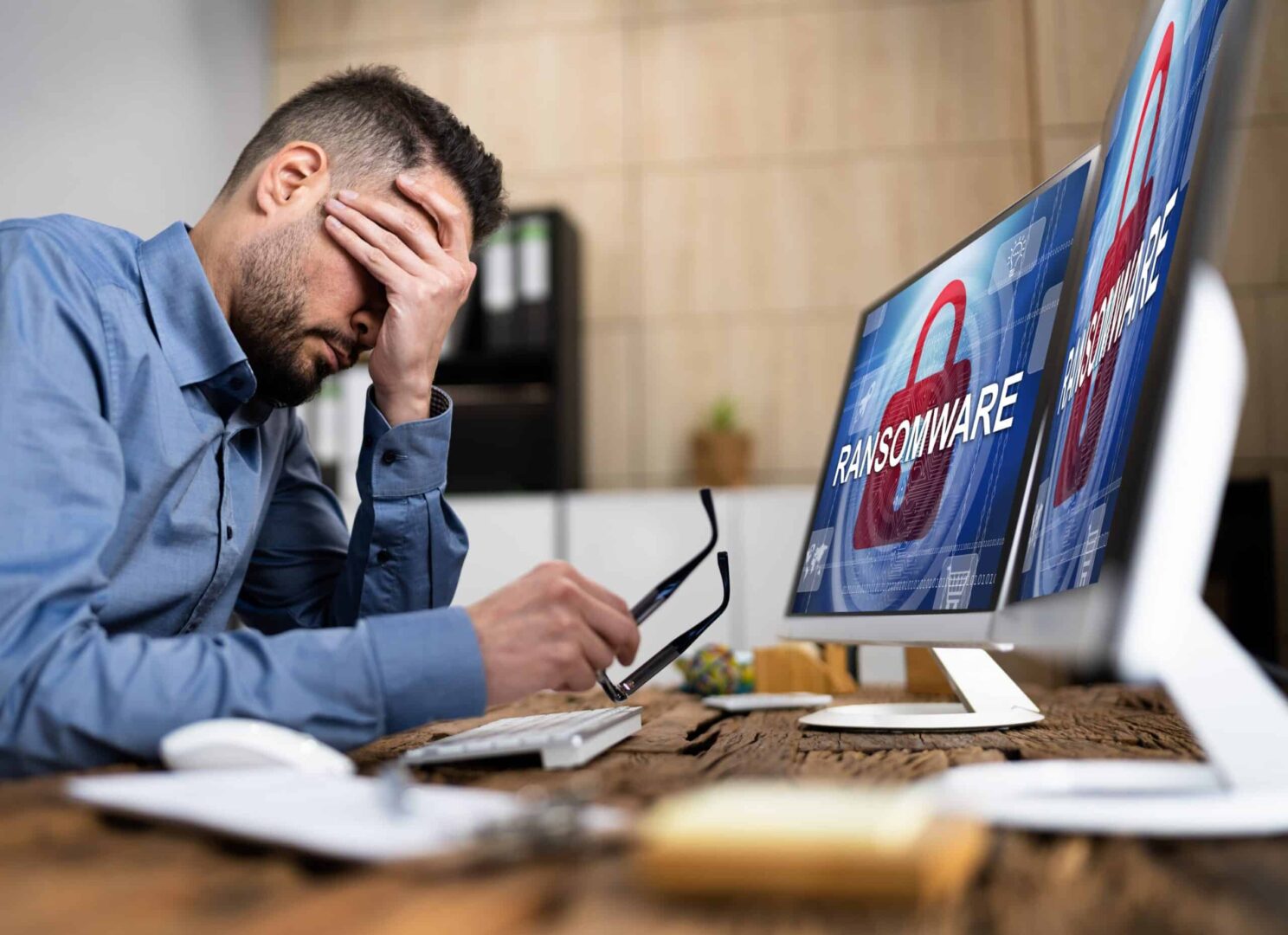 Ein Mann sitzt vor einem mit Ransomware infizierten Computerbildschirm.