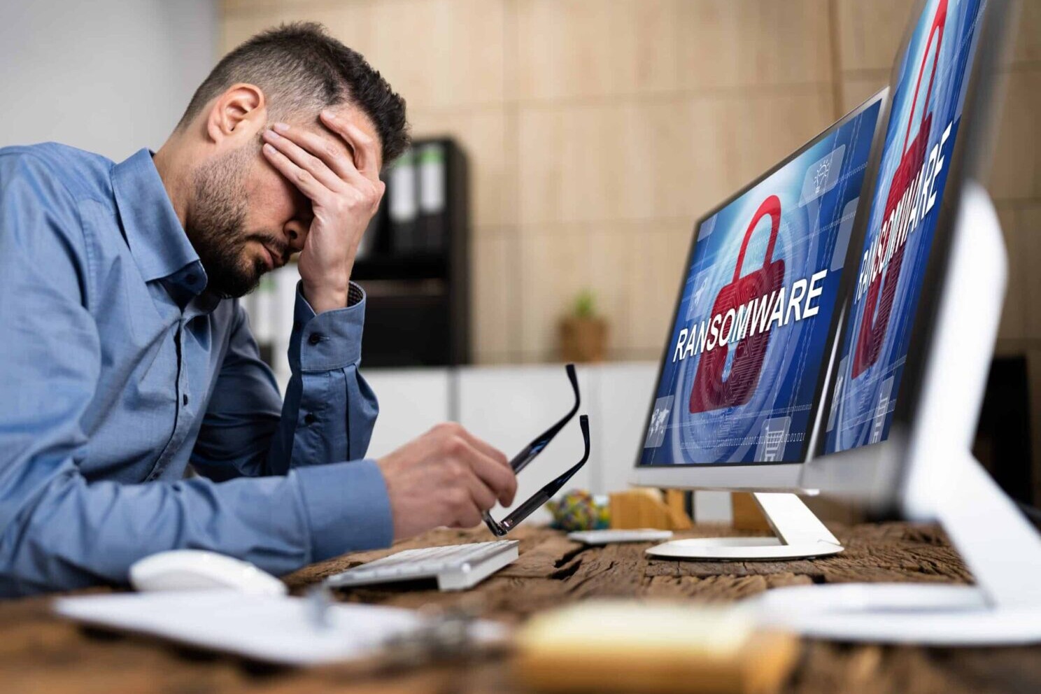 Ein Mann sitzt vor einem mit Ransomware infizierten Computerbildschirm.